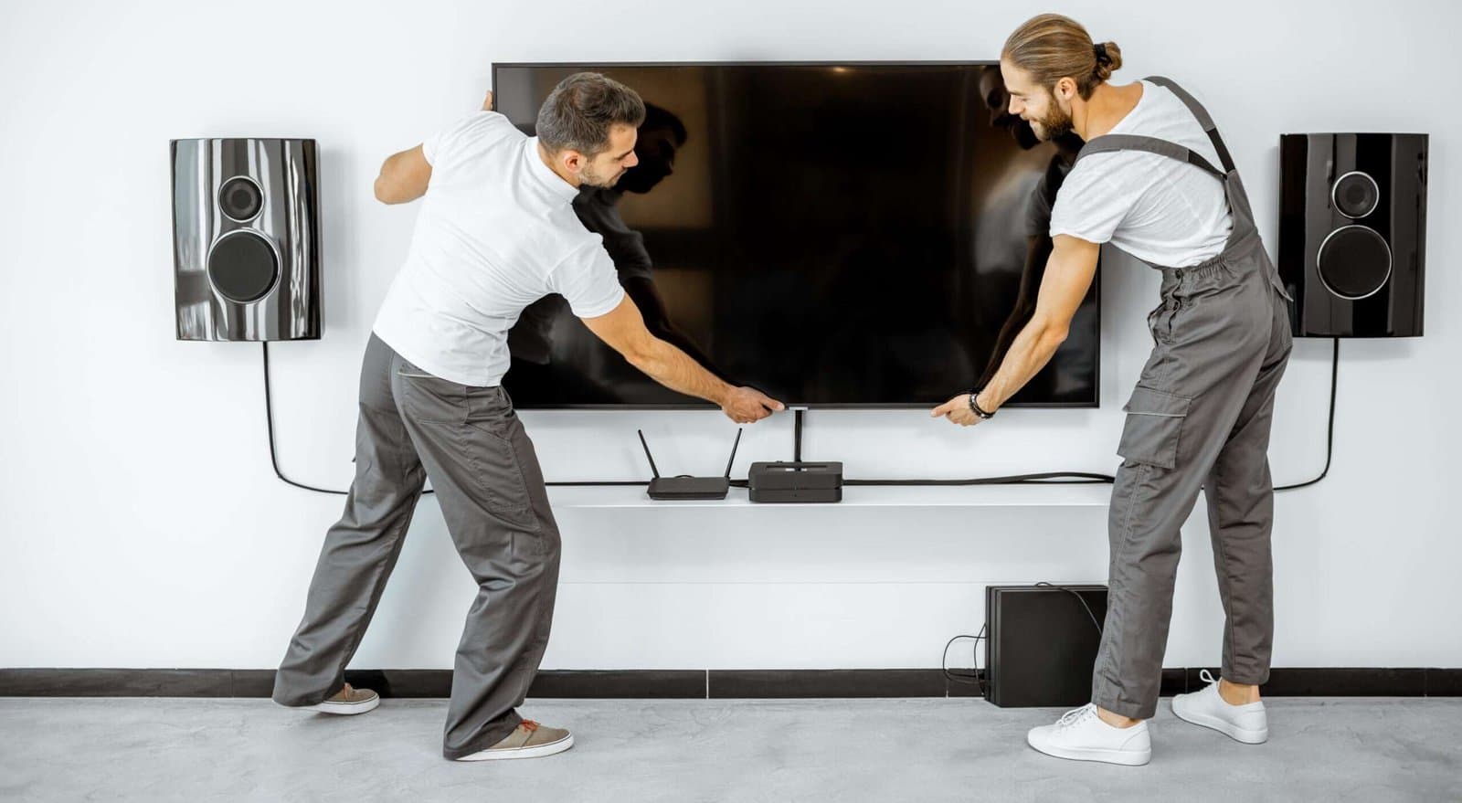 Profissionais instalando uma televisão na parede
